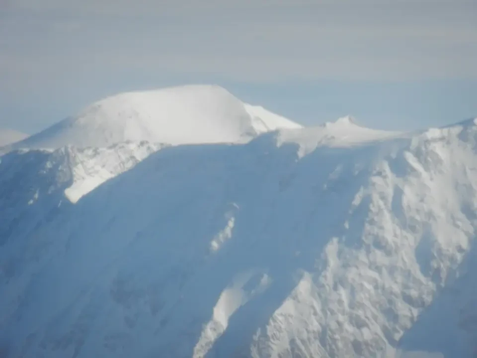 Vaste montagne innevate si stagliano sotto un cielo chiaro.