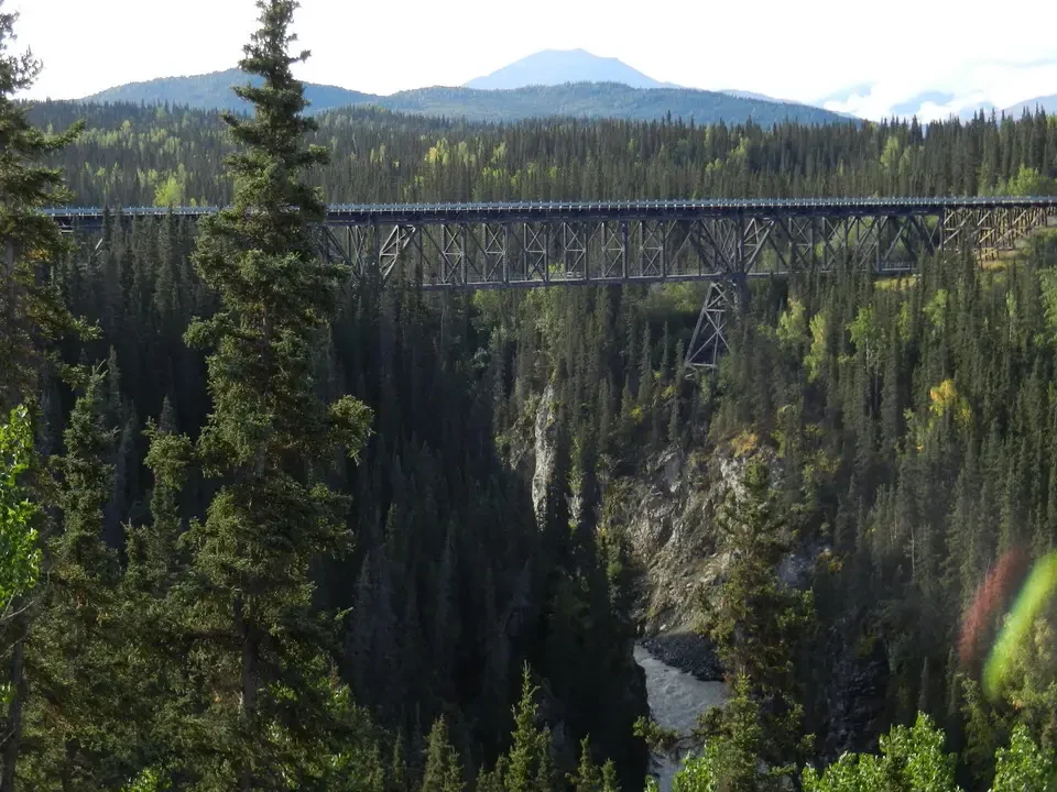 A railway bridge crosses a wooded and rocky valley.