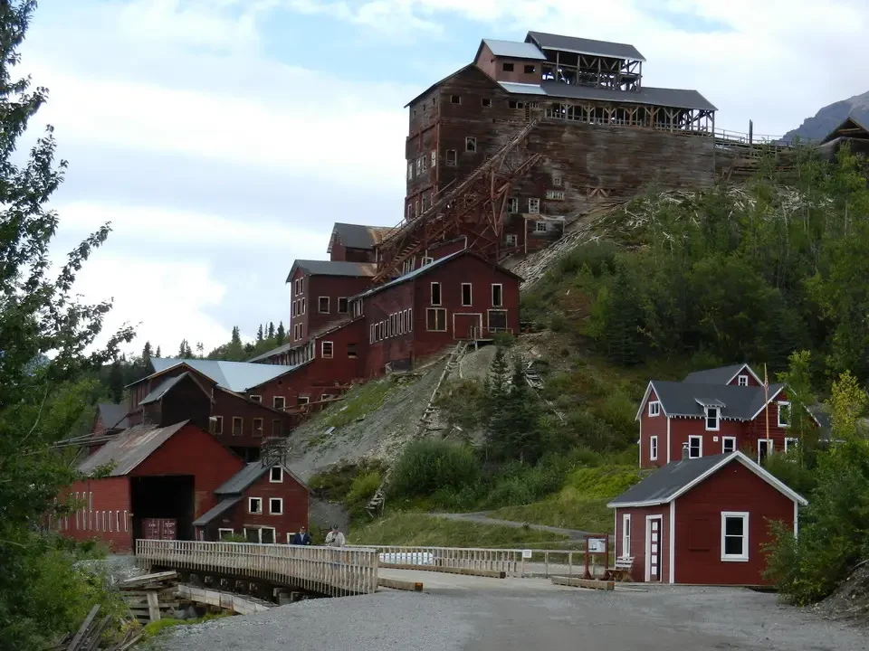 A historic wooden mine sits on a wooded hill.