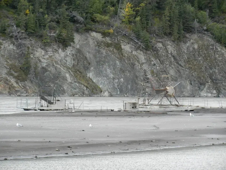 A wooden fishing structure is visible along the rocky river bank.