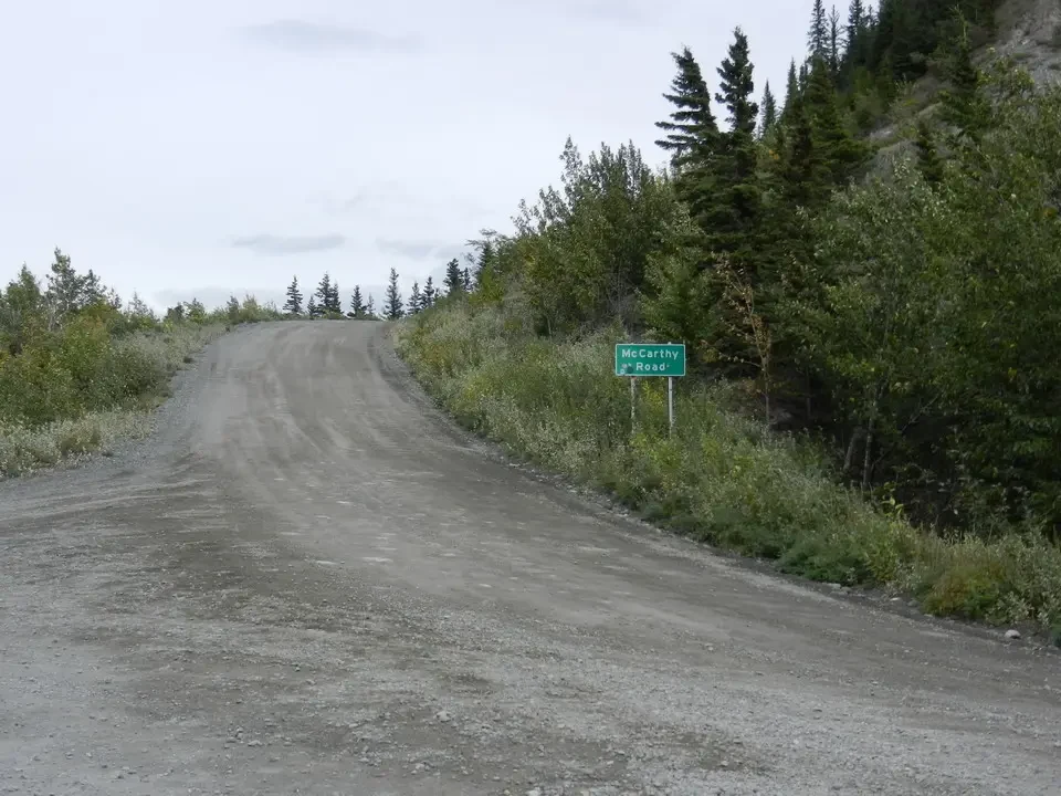 A dirt road curves through a wooded landscape.