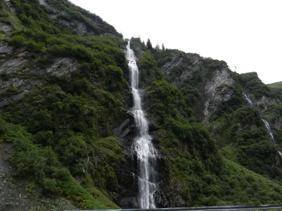 A wet waterfall flows down a steep green wall.