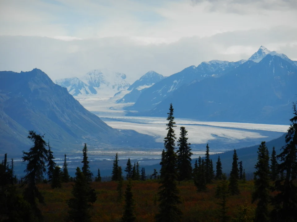 Vast snow-capped mountains and glaciers stretch across an alpine landscape.