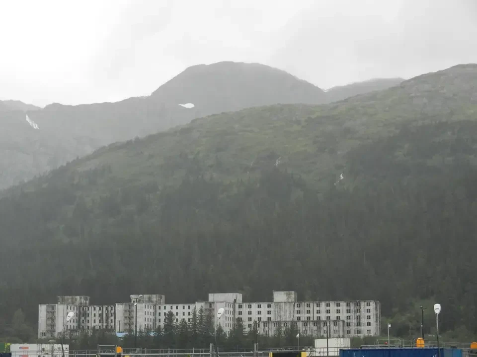 A building looms above a foggy, wooded valley.