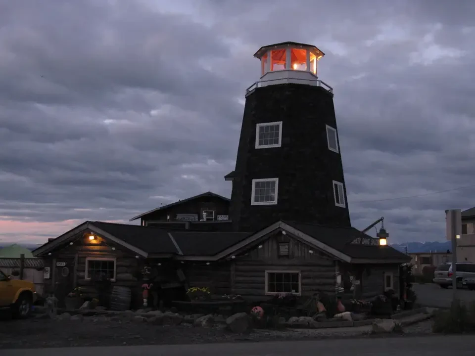 A wooden watchtower with an illuminated lantern stands out against a cloudy sky.