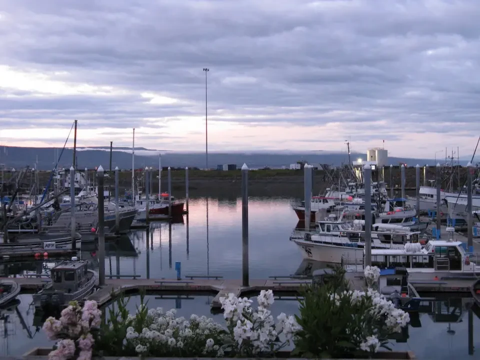 A small boat is moored in a port at sunset.