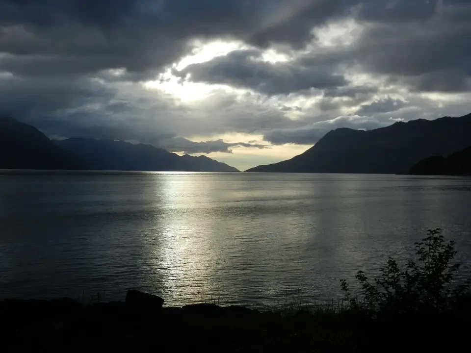 Dramatic sunset over the mountains over a rippling water surface.