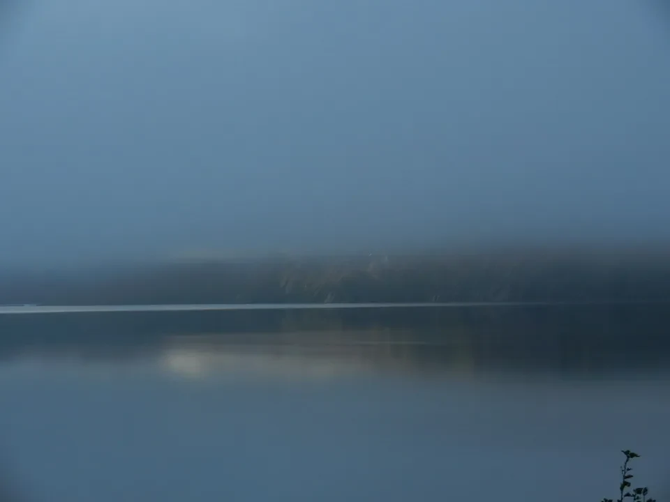 A lake shrouded in fog at dawn.