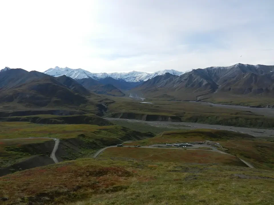 Snow-capped mountains and a river flow through a vast wild landscape.