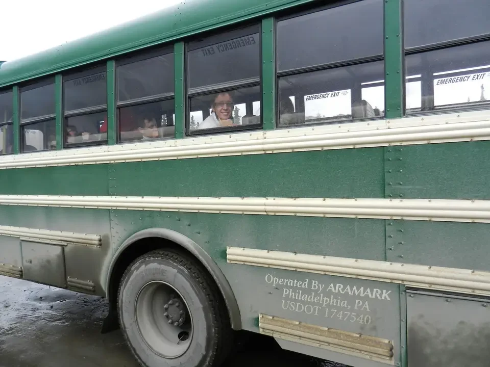 A green bus with windows shows people inside.