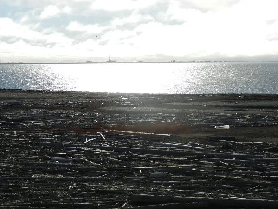 A horizontal landscape shows a vast body of water under a cloudy sky.