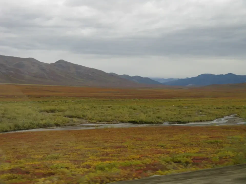 A vast landscape with mountains and a river cross a grassy plain.