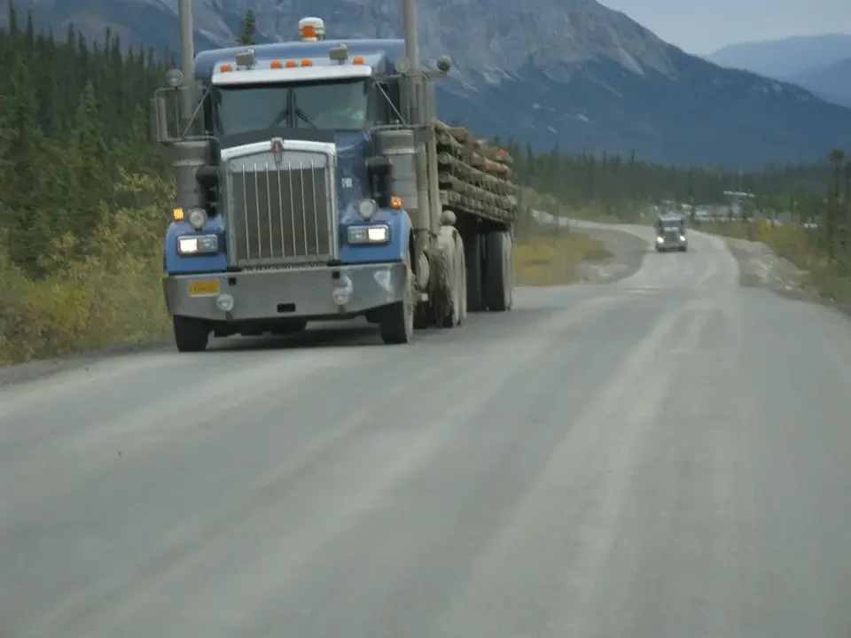 A truck transports goods on a scenic road in the mountains.