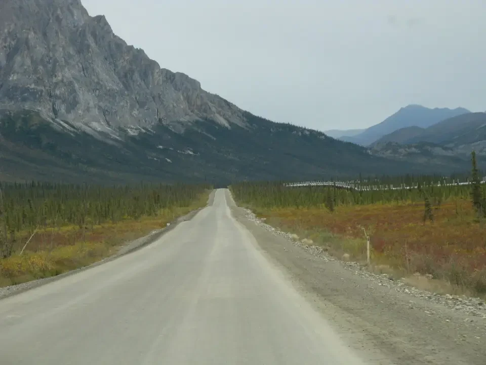 A dirt road stretches through a vast mountain landscape.