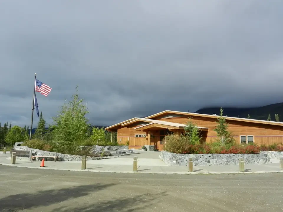 Exterior view of the visitor center with wooden buildings and mountain landscape in the background.