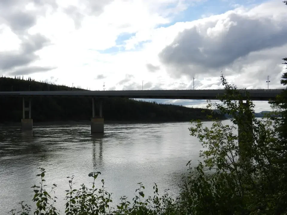 A bridge crosses a river under a cloudy sky.