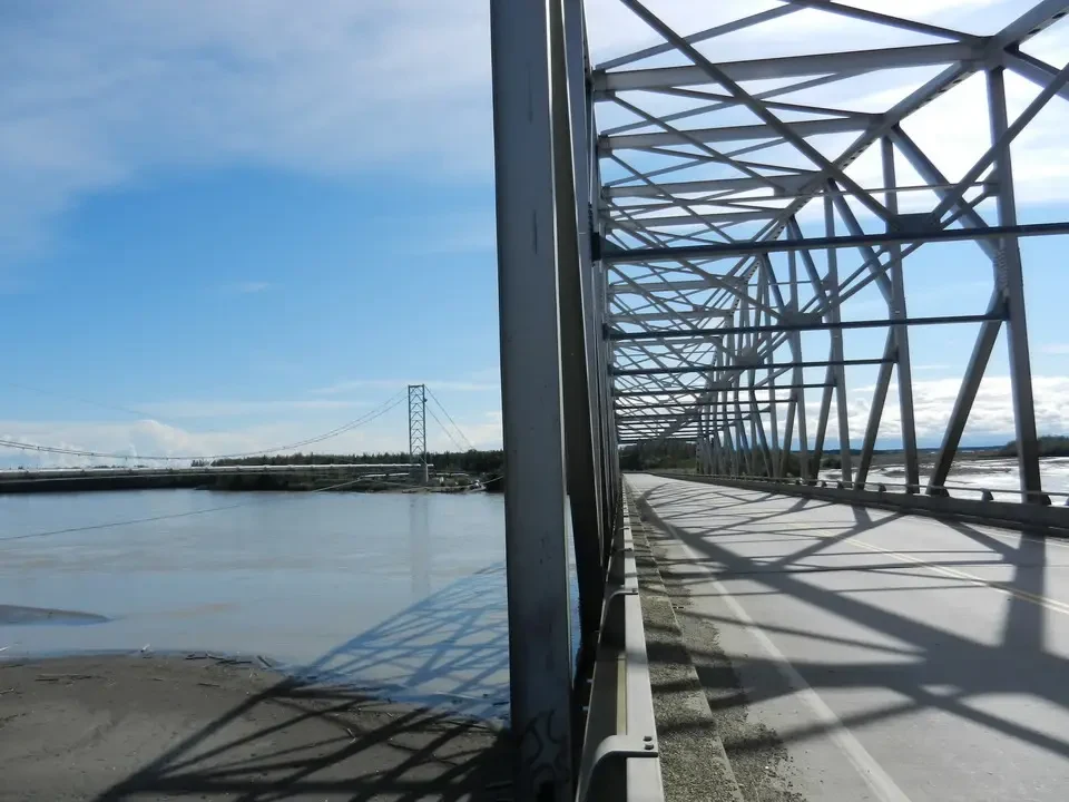 Steel bridge over a river, with a road crossing the structure.