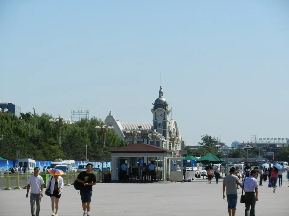 Una veduta ampia della Piazza Tiananmen a Pechino con edifici storici e persone che passeggiano.
