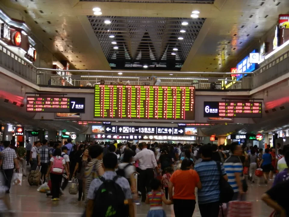 Una folla di persone cammina in un ampio atrio di stazione in Cina.