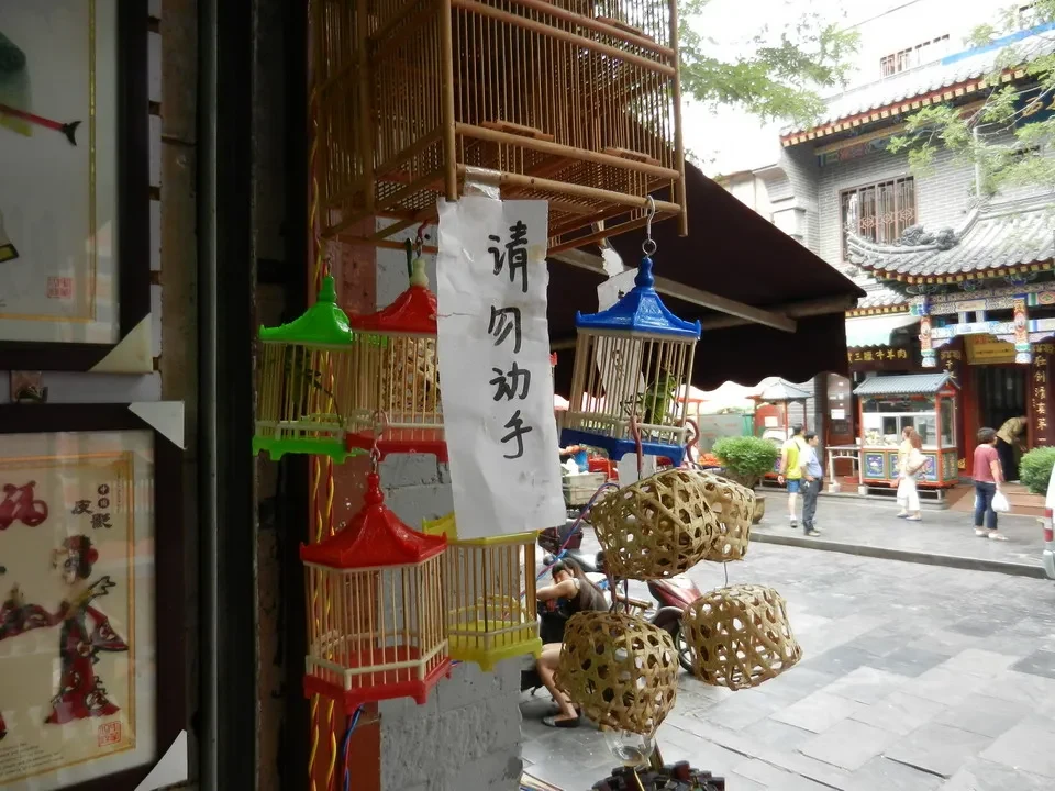 Una galleria fotografica di strada in Cina mostra una struttura decorativa con cesti intrecciati e negozi tradizionali.