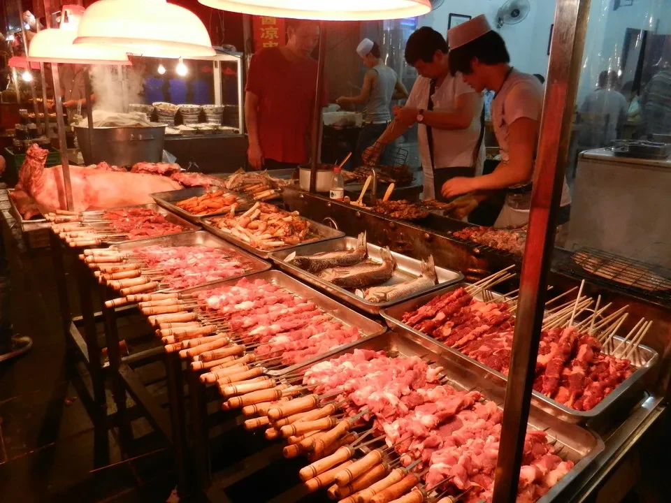 Una galleria di cibo in un mercato cinese mostra carni fresche esposte su griglie metalliche.