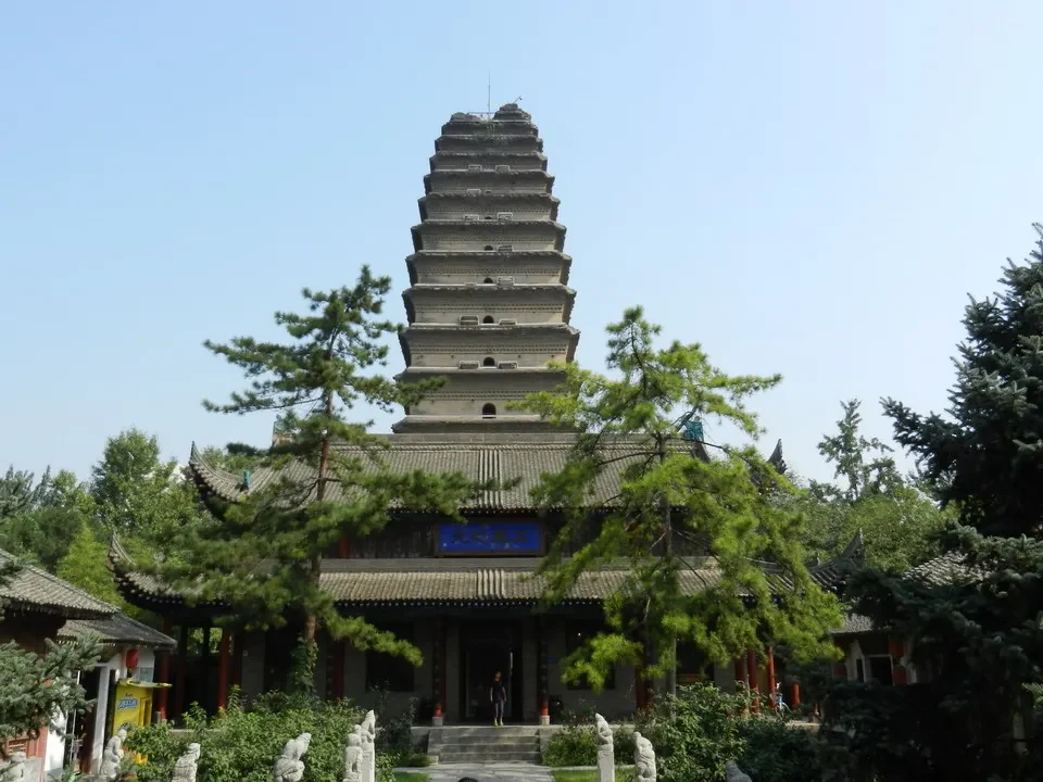 Una piccola pagoda con un'oca selvaggia è visibile in un giardino cinese.