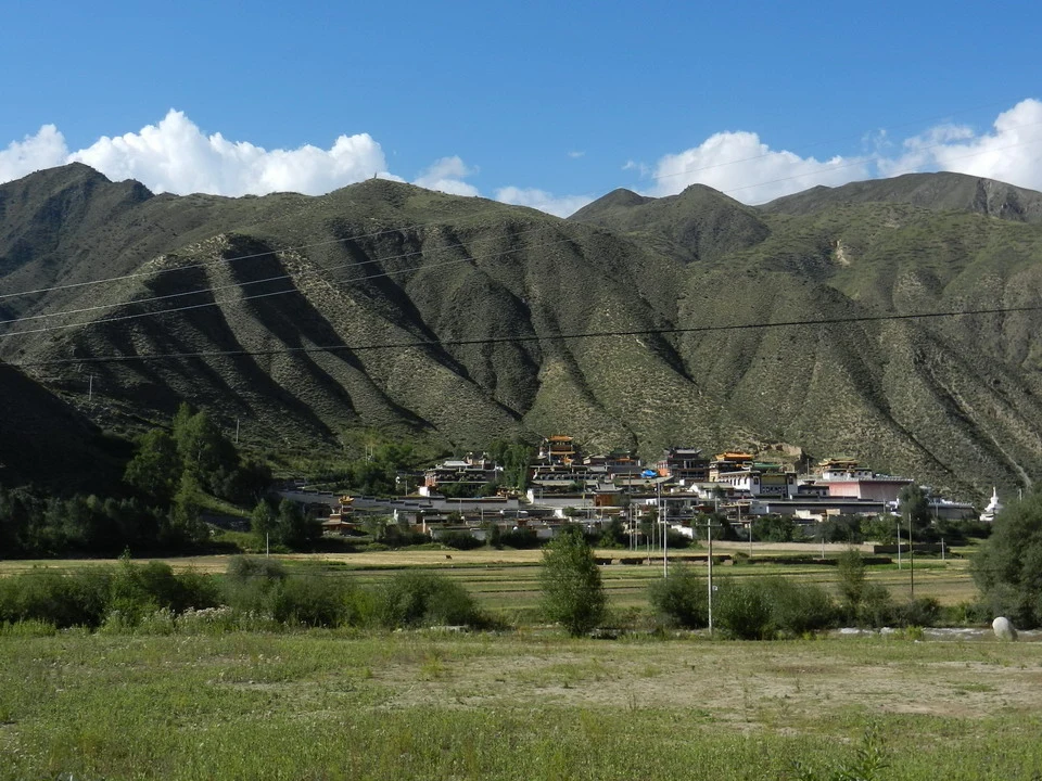 Paesaggio montano con insediamenti rurali in Cina sotto un cielo azzurro.