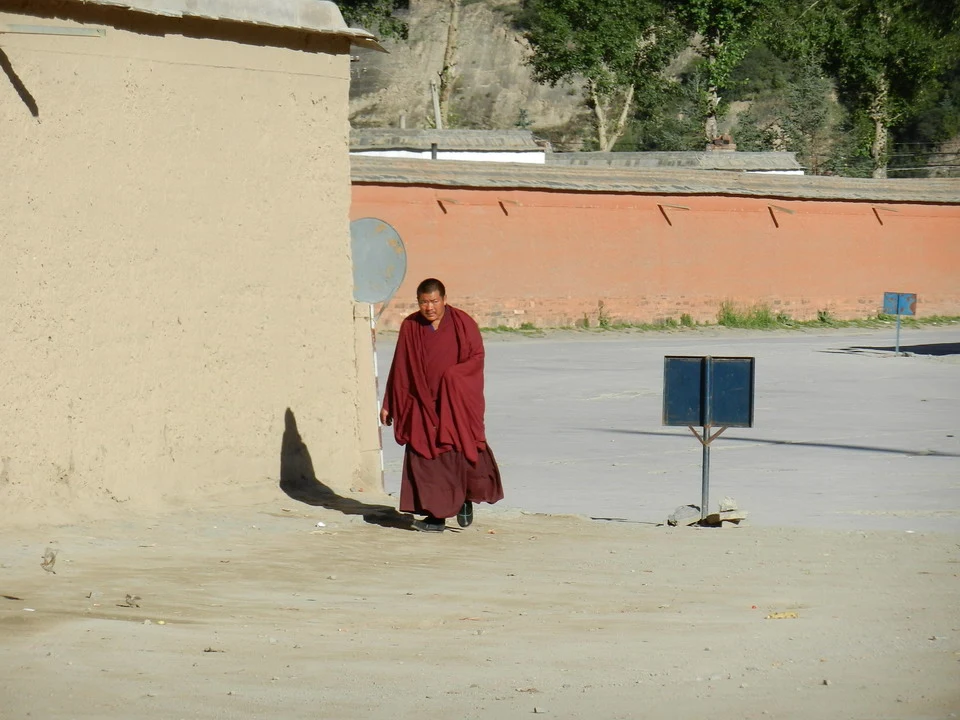 Un uomo in abiti rossi cammina lungo una strada con edifici in mattoni in Cina.