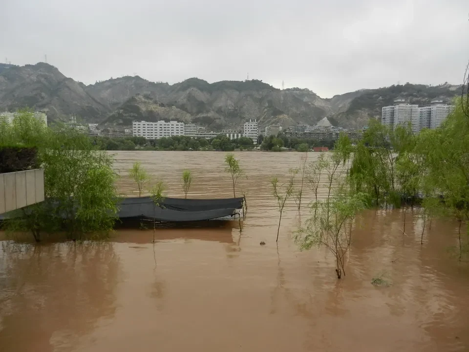 Un fiume fangoso scorre tra le colline e gli edifici in Cina.