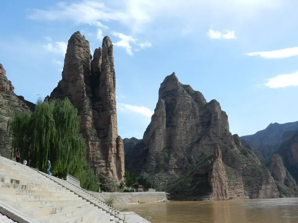 Un tempio si erge tra imponenti formazioni rocciose lungo un fiume in Cina.