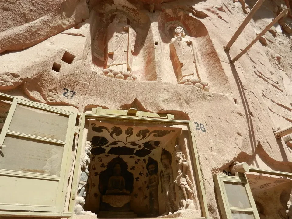 Facciata di roccia scolpita con statue religiose in un tempio buddista cinese.