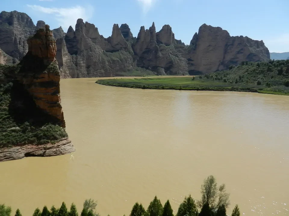Formazioni rocciose verticali emergono dall'acqua di un fiume torbido in Cina.