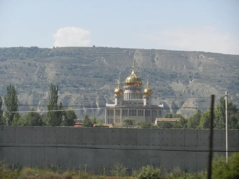 Una moschea con cupole dorate si trova in un paesaggio collinare arido della Cina.
