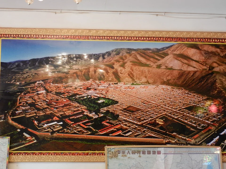 Vista aerea di una città antica con tetti rossi incastonati tra colline aride.