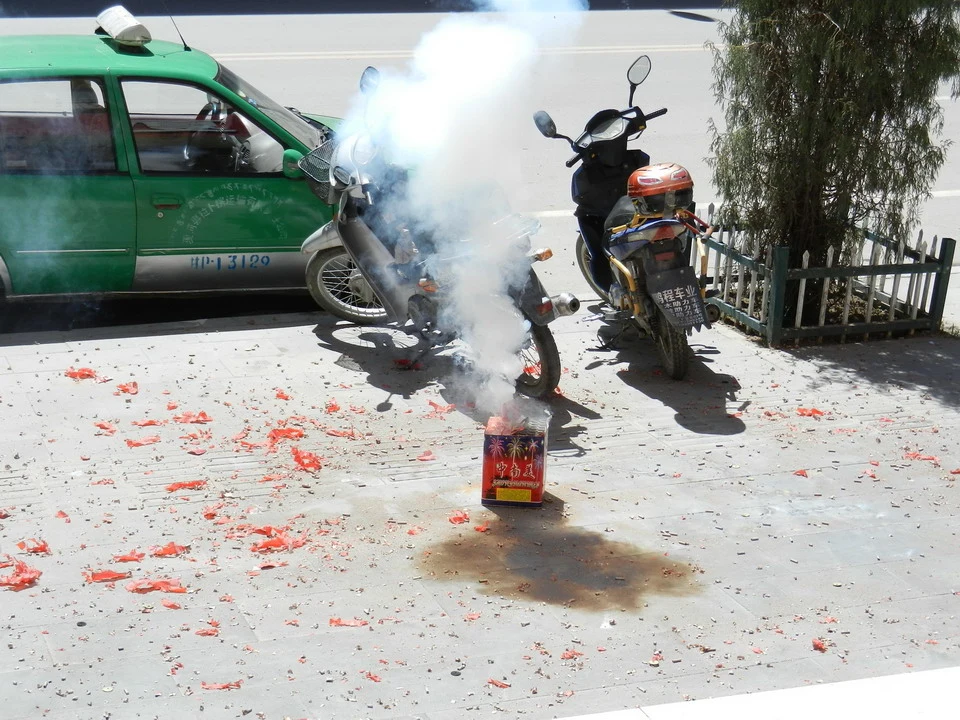 Una motociclista passa su una strada coperta di petali rossi in Cina.
