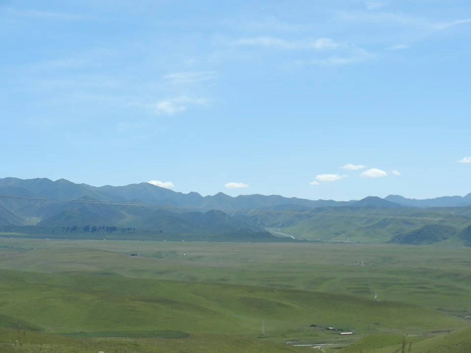 Paesaggio montano e pianeggiante in Cina sotto un cielo azzurro.