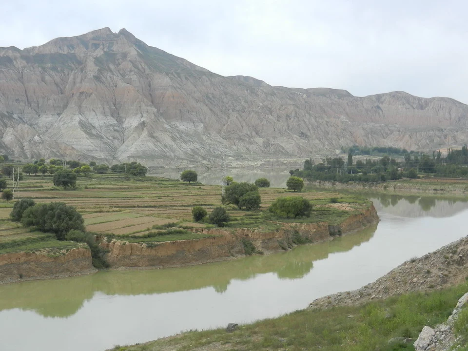 Paesaggio fluviale e montuoso in Cina con vegetazione lungo le rive.