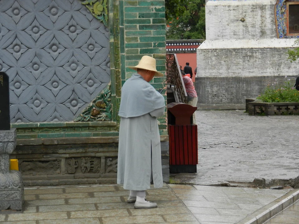 Un uomo in abiti lunghi cammina davanti a una struttura decorata in Cina.