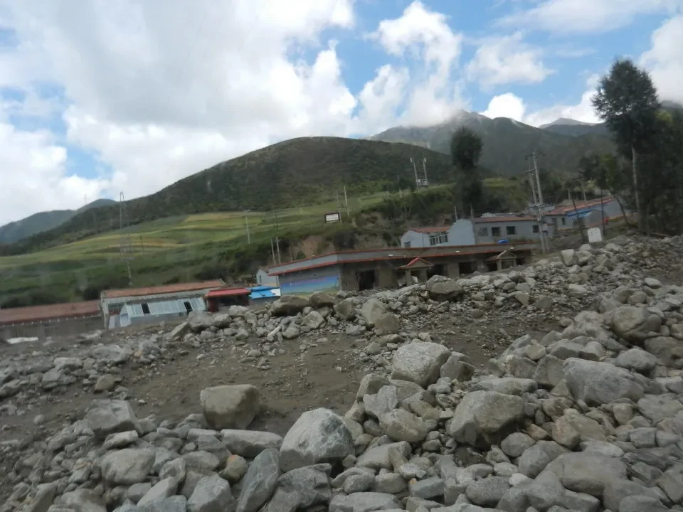 Paesaggio montano con edifici in una zona rurale della Cina sotto un cielo nuvoloso.