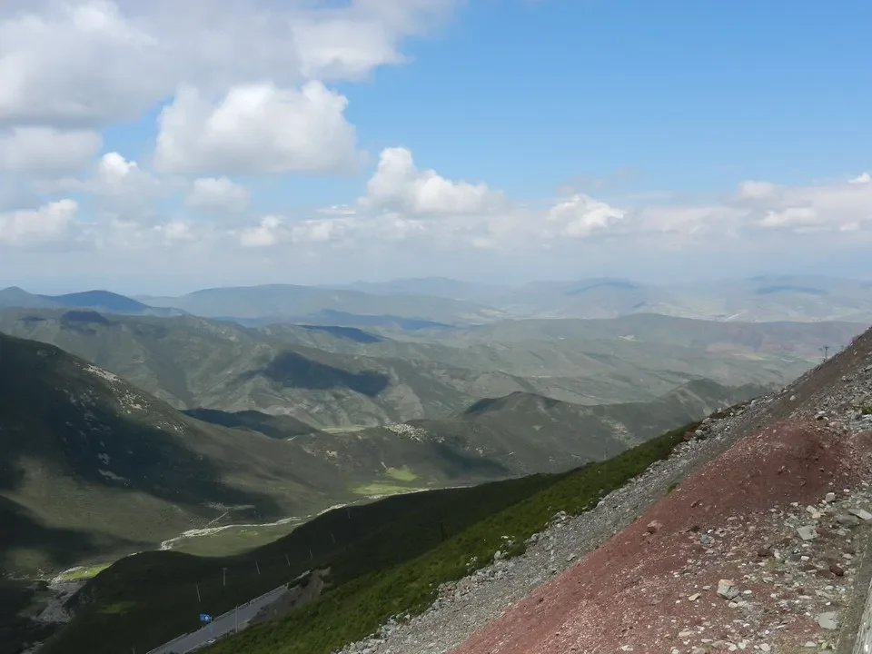 Paesaggio montano vasto con cielo azzurro e nuvole bianche in Cina.