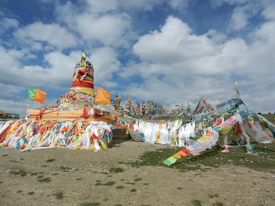 Una grande installazione artistica colorata è allestita all'aperto sotto un cielo nuvoloso.