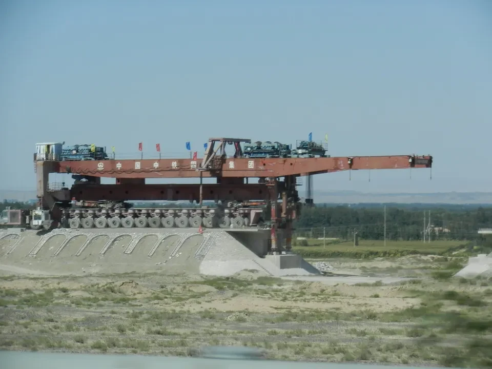 Una grande macchina da costruzione è posizionata su un terrapieno in un paesaggio aperto.