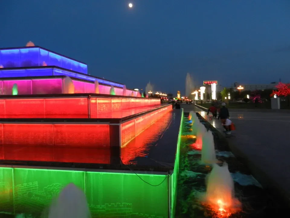 Una vista notturna di un parco acquatico illuminato con giochi d'acqua colorati.