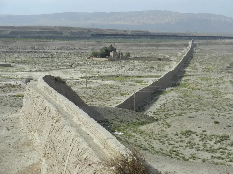 Una sezione della Grande Muraglia cinese si estende attraverso un paesaggio arido.