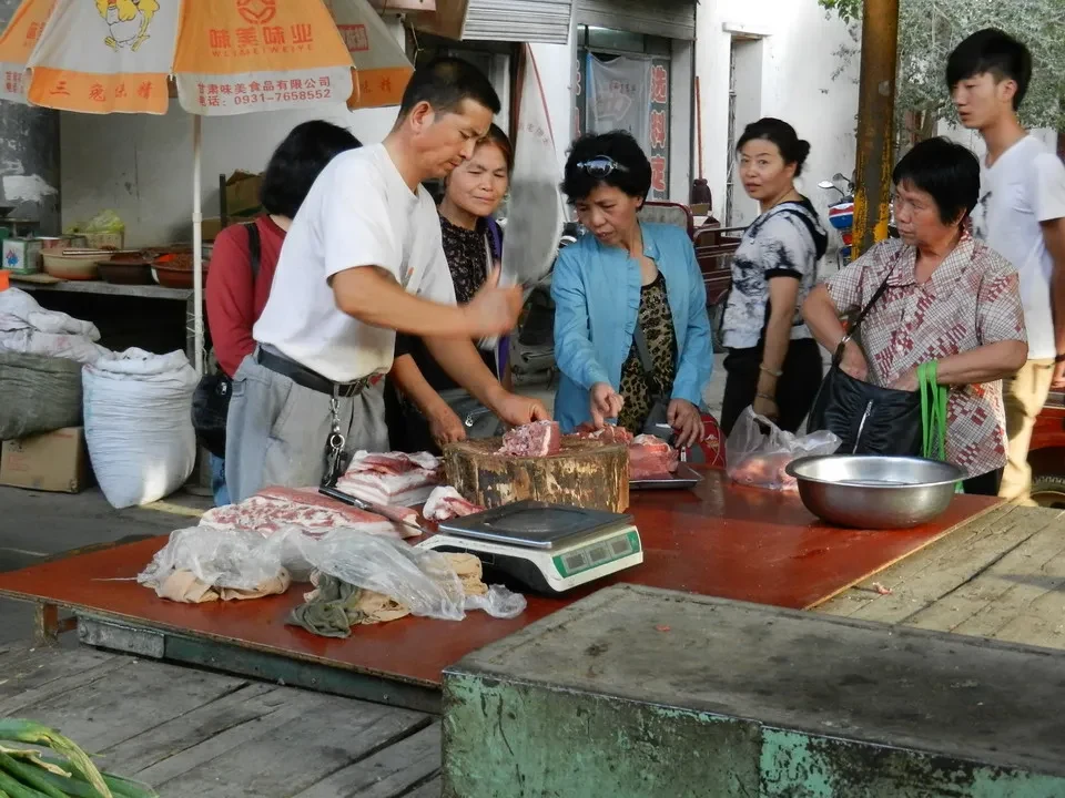 Un gruppo di persone sta preparando carne in un mercato all'aperto in Cina.