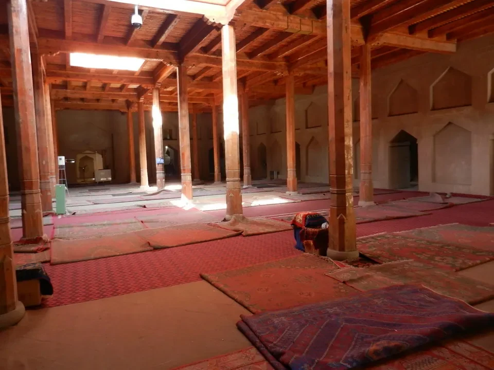 Interni di una moschea con soffitto ligneo e pilastri in mattoni rossi.