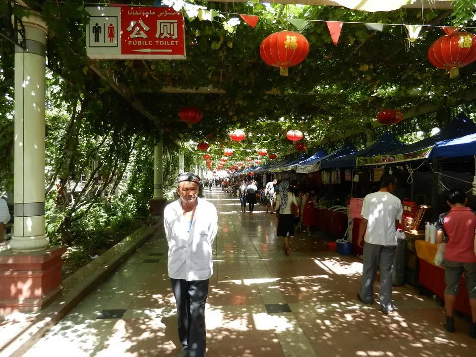 Una passeggiata ombreggiata con bancarelle lungo una strada in Cina.
