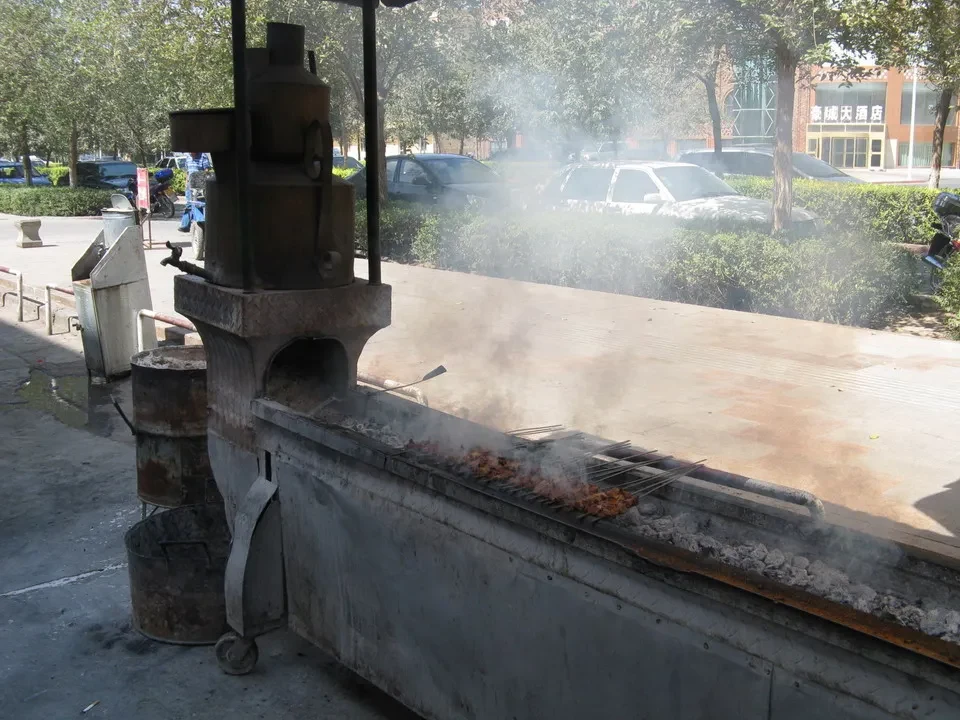 Una griglia di cottura a carbone emette fumo mentre viene utilizzata all'aperto.
