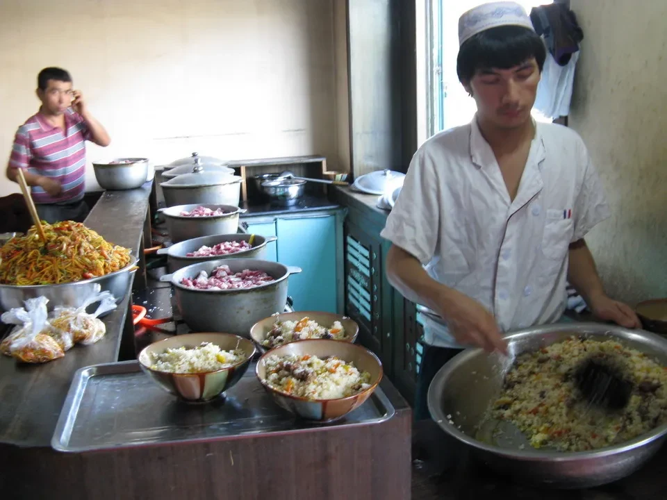 Uomini cucinano cibo in una cucina in stile cinese.