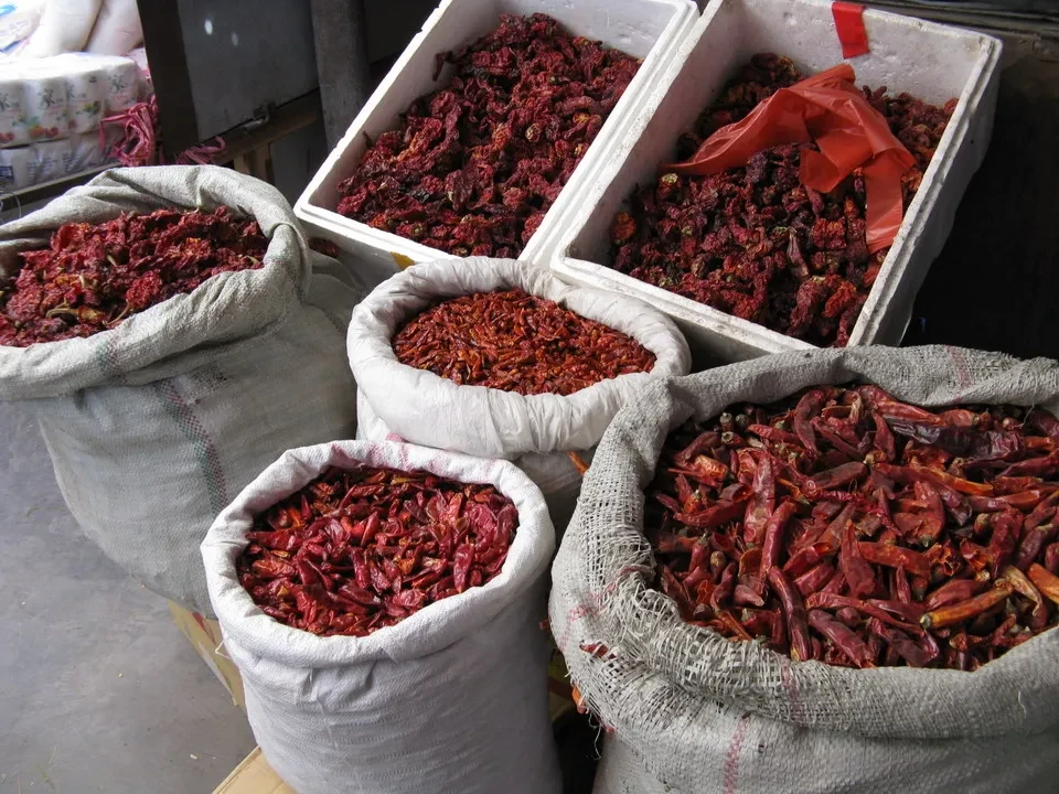 Un assortimento di spezie rosse e secche in sacchi e contenitori.